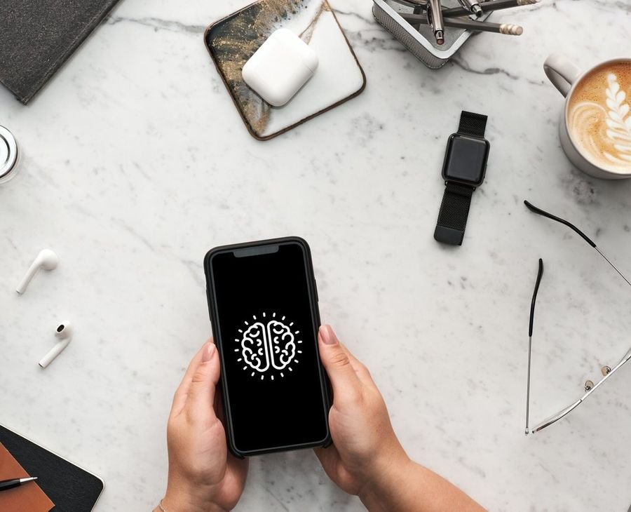 Hands holding a phone showing the brain mark on a marble desk