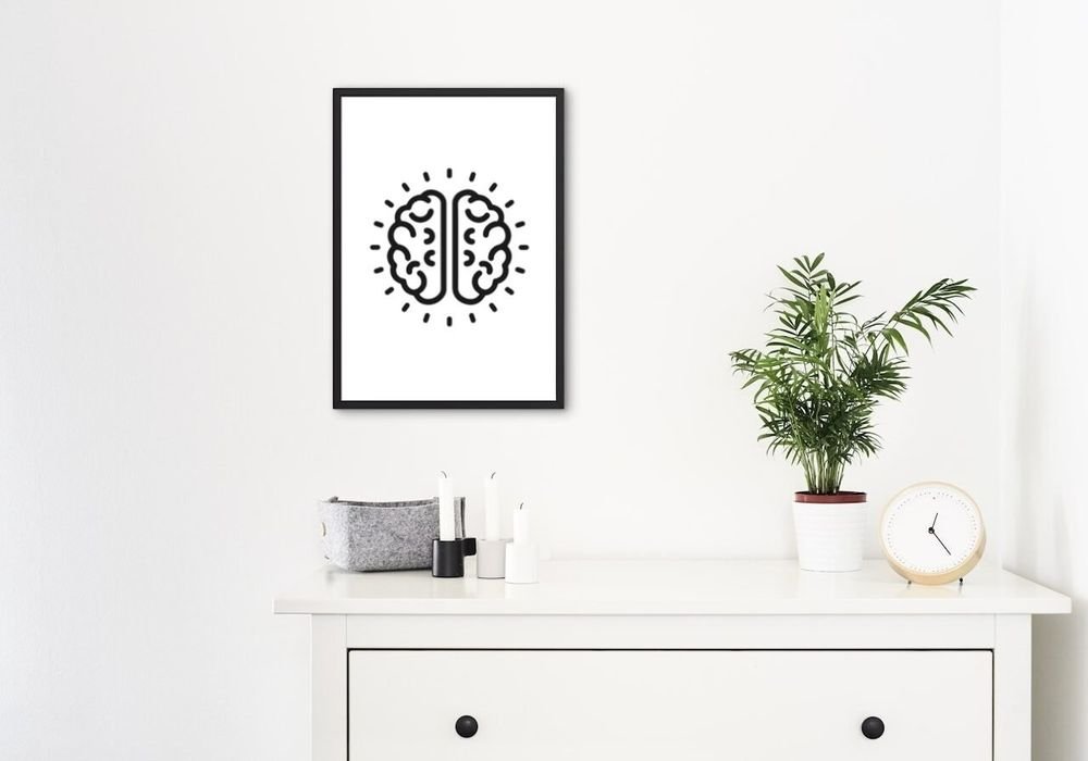 The brain mark framed above a white dresser with a plant and a clock